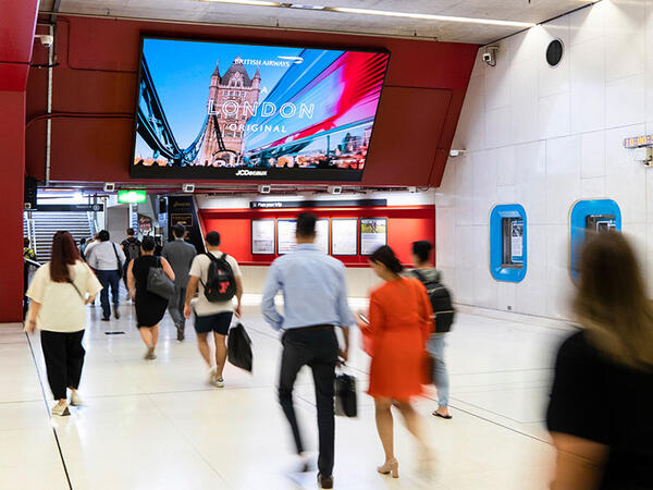 Digital advertising panels positioned overhead throughout a train station, engaging commuters with eye-catching content.