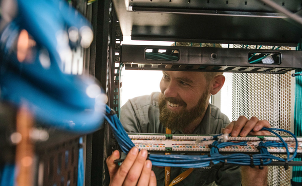 A telecommunications apprentice working on a server rack