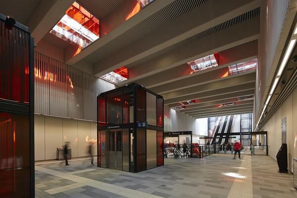 Orange light warms the concourse of Norwest station. The colour glows through the ceiling lanterns and is also integrated into the elevator and stair glazing.
