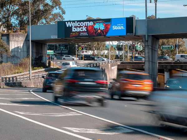 Digital advertising boards featuring captivating visuals and advertisements over a busy road, with lots of traffic