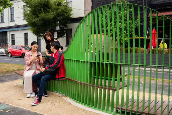 A group of people interacting with City of Melbourne’s Social Spaces chair, on Lygon Street. 