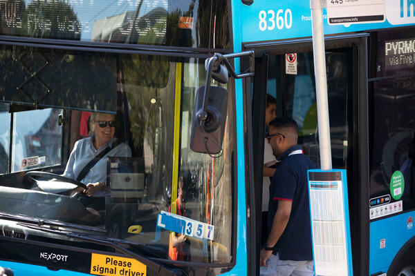 Bus driver greeting passengers on an electric bus
