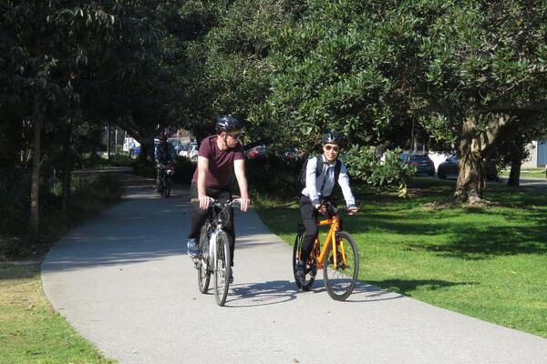 Two cyclists riding side by side through park