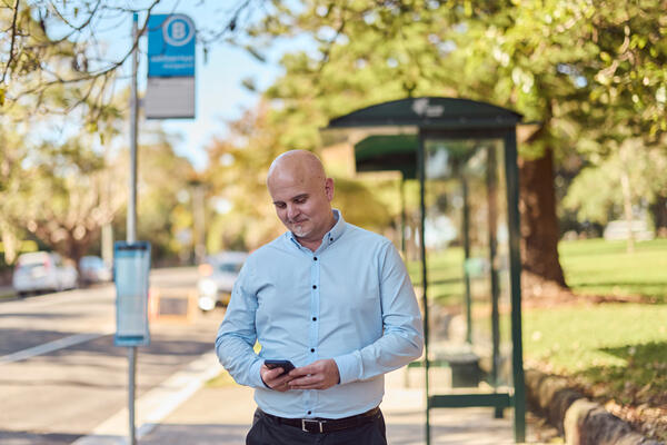 Commuter using mobile phone at bus stop