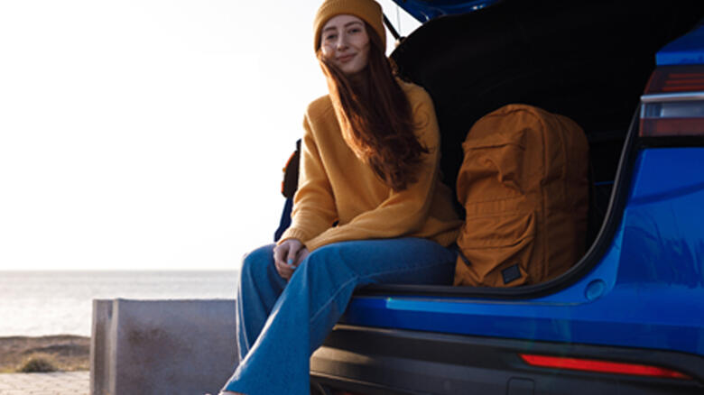 Woman sitting on the boot of a car