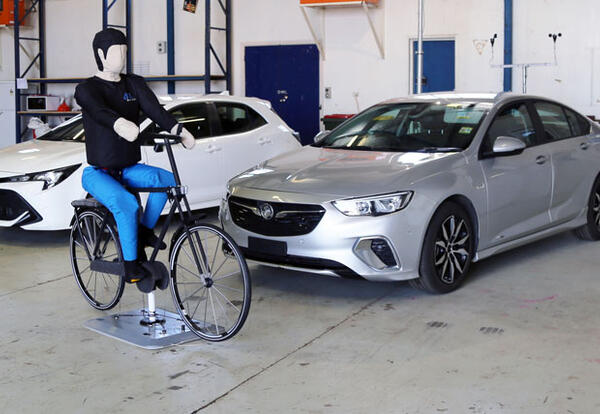 A crash-test cyclist and cars in a test facility