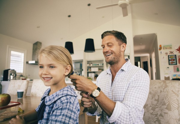 Photo of a man doing his daughter's hair before school